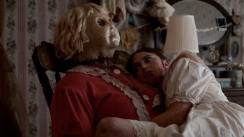 Une jeune femme ensanglantée dans une robe blanche fait un câlin a une terrifiante poupée de porcelaine géante