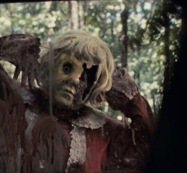 La poupée Dolly dans le film d'horreur du même nom observe sa victime derrière une fenêtre de voiture.