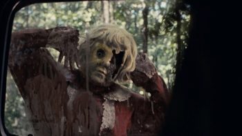 La poupée Dolly dans le film d'horreur du même nom observe sa victime derrière une fenêtre de voiture