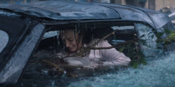 Une femme paniquée est bloquée dans sa voiture qui se fait inonder ; les vitres sont brisées et le niveau de l'eau monte dangereusement dans l'habitacle ; plan du film NATURE PREDATRICE de Tommy Wirkola.
