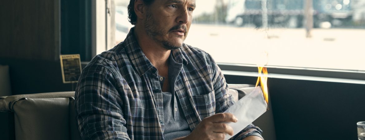 L'acteur Pedro Pascal assis à une salle de diner en train de brûler une enveloppe.