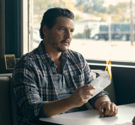 L'acteur Pedro Pascal assis à une salle de diner en train de brûler une enveloppe.