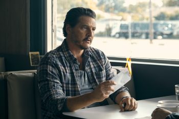 L'acteur Pedro Pascal est assis à une salle de diner en train de brûler une enveloppe ; il porte une chemise à carreau ; la table se trouve juste à côté d'une fenêtre ; plan du film FREAKY TALES, projeté au Grindhouse Paradise 2026.