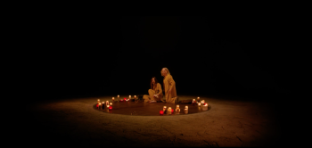 Une mère et sa fille dans un cercle tracé par des cendres et des bougies, dans l'obscurité ; toutes deux sont au loin, à peine discernables, tandis que règne l'obscurité ; plan du film THE SURRENDER projeté au Grindhouse Paradise 2026.
