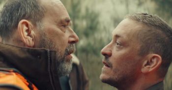 Deux hommes se font face ; celui de droite est l'acteur Olivier Gourmet ; les visages apparaissent en gros plan ; une tension est perceptible dans ce face-à-face ; plan du film GIBIER, projeté au BIFFF 2026.