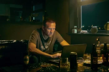 Harry Hole sur son ordinateur portable, dans son salon, au milieu de cannettes et de bouteilles d'alcool vides.