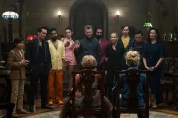 Deux femmes blondes sont assises chacune sur une chaise, dos à la caméra ; face à elle se tiennent une dizaine de personnes debout ; ces personnes portent des vêtements bariolés ; en arrière-plan, on aperçoit des lampes et on devine que la pièce est celle d'un manoir ; plan du film WEDDING NIGHTMARE : DEUXIEME PARTIE, projeté au BIFFF 2026.