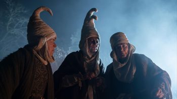 Trois vieilles femmes sont filmées de nuit en contre-plongées ; toutes les trois portent d'étranges coiffes blanches, hautes et se terminant par de manière courbée ; elles sont vêtues de vêtements sombres et regardent à leur pied ; derrière lle, on devine des arbres et une brume étrange ; plan du film GAUA, projeté au BIFFF 2026.