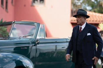 Un homme en costume et chapeau devant une voiture ancienne dans une époque semblable aux années 30 dans Diamond de Andy Garcia