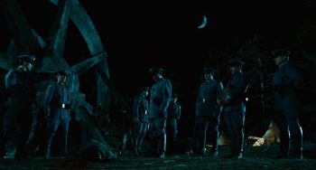 Dees agents de Franco se tiennent debout face à un homme sous une lune dans la nuit noire dans Le Labyrinthe de Pan de Guillermo Del Toro