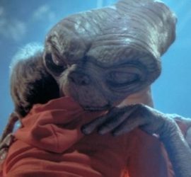 Un extraterestre enlace un petit garçon en hoodie rouge dans E.T de Steven Spielberg