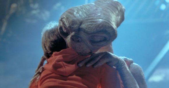 Un extraterestre enlace un petit garçon en hoodie rouge dans E.T de Steven Spielberg