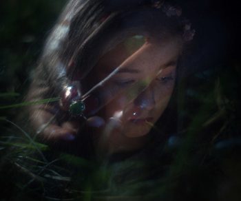 Visage d'une jeune fille en surimpression avec une main portant une bague à pierre verte.