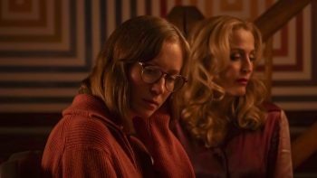 Deux femmes s'ignorent en plan rapproché ; la blonde en arrière-plan, jouée par Gillian Anderson, à le regard perdu à sa gauche ; la jeune femme à l'avant-plan porte des lunettes et à la tête légèrement incliné vers le sol, le regard tout aussi perdu ; plan du film TEENAGE SEX AND DEATH AT CAMP MIASMA, présenté à Cannes 2026.