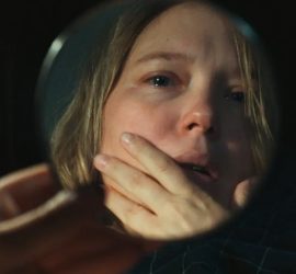 Léa Seydoux se regardant dans un miroir de poche, les larmes aux yeux.