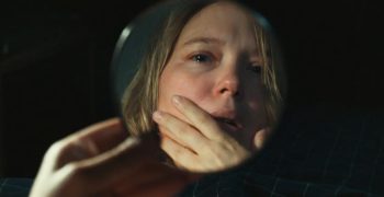 Léa Seydoux se regardant dans un miroir de poche, les larmes aux yeux.