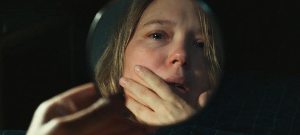 Léa Seydoux se regardant dans un miroir de poche, les larmes aux yeux.