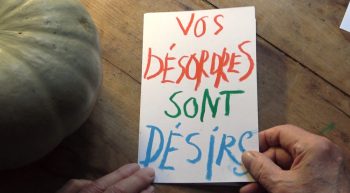 Un gros plan sur une feuille sur laquelle est écrit avec une écriture manuscrite et colorée "vos désordres sont désirs" dans le film merci d'être venu de Alain Cavalier