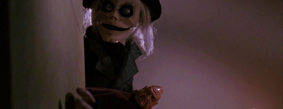 Les poupées Blade et Pinhed se cachent derrière un mur blanc, observant, dans le film Puppet Master.