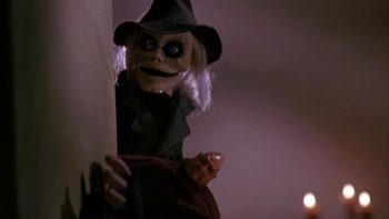Les poupées Blade et Pinhed se cachent derrière un mur blanc, observant, dans le film Puppet Master.