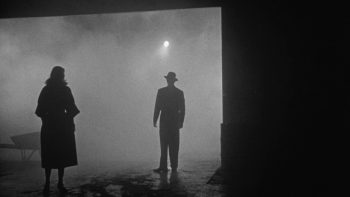 Plan large, de nuit, brumeux, sur deux silhouettes, un homme et une femme qui se font face dans le film The big combo réalisé par Joseph H. Lewis abordé dans Trois maîtres du cinéma modeste.