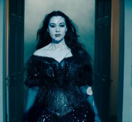 L'actrice Monica Bellucci dans le rôle de Dolores dans le film Beetlejuice Beetlejuice, en robe noire, passant une porte.