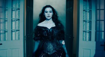 L'actrice Monica Bellucci dans le rôle de Dolores dans le film Beetlejuice Beetlejuice, en robe noire, passant une porte.