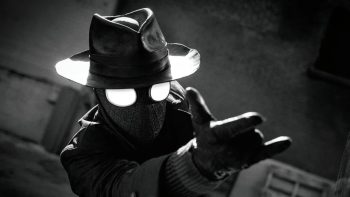 Un avatar de Spider-Man, Spider-Noir, tend le bras à l'horizontale, comme s'il allait lancer une toile d'araignée ; le plan est en noir et blanc, et les yeux de l'homme-araignée sont d'un blanc lumineux ; il porte un chapeau de détective et sans doute un pardessus ; derrière lui, on aperçoit un mur ; plan de la série SPIDER-NOIR de Prime Vidéo.