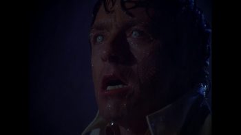 Le visage figé d'un homme en gros plan dans l'obscurité totale ; il a la bouche entrouverte et l'on aperçoit sa dentition ; ses yeux sont vitreux et regardent droit devanx eux ; plan de la série L'INCROYABLE HULK, rééditée par Elephant Films. 