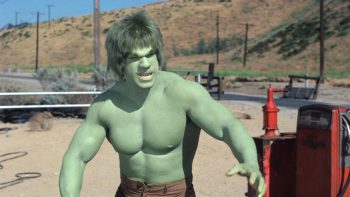Hulk, le géant vert incarné par Lou Ferrigno, se tient au milieu d'un paysage désertique ; il est torse nu, a le corps musclé et affiche un faciès déterminé, voire colérique ; on devine une sorte de borne rouge à côté de lui, à la gauche du plan ; derrière lui, on aperçoit des collines désertiques avec une série de pilonnes électriques ; plan de la série L'INCROYABLE HULK, rééditée par Elephant Films.