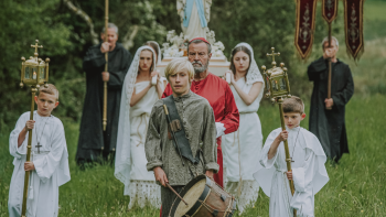 Une procession catholique, des enfants garçons et filles portent une statuette de la vierge marie, un autre enfant devant eux porte un tambour