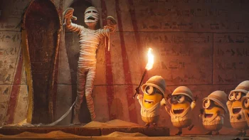 Cinq Minions, à la droite du plan, découvrent une momie sortant de son sarcophage dans un couloir qui peut s'apparenter à l'intérieur d'une pyramide ; les Minions portent tous un casque blanc et semblent ravis de leur découverte ; la momie, composée de bandelettes blanches, est debout, tendant les bras ; les murs sont couverts de hiéroglyphes ; le Minions en tête de cohorte brandit une torche allumée ; plan du film DES MINIONS ET DES MONSTRES, de Pierre Coffin.