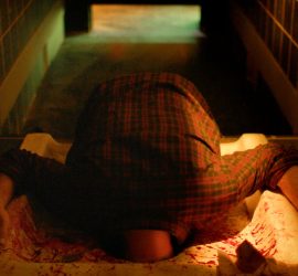 Un homme coincé dans les toilettes turcs d'un bar ; on ne voit dépasser que ses épaules et ses bras ; plan issu du film Flush de Gregory Morin.