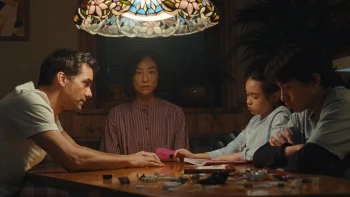 Une famille à table, au centre une mère d'origine asiatique fixe le vide comme inquiète