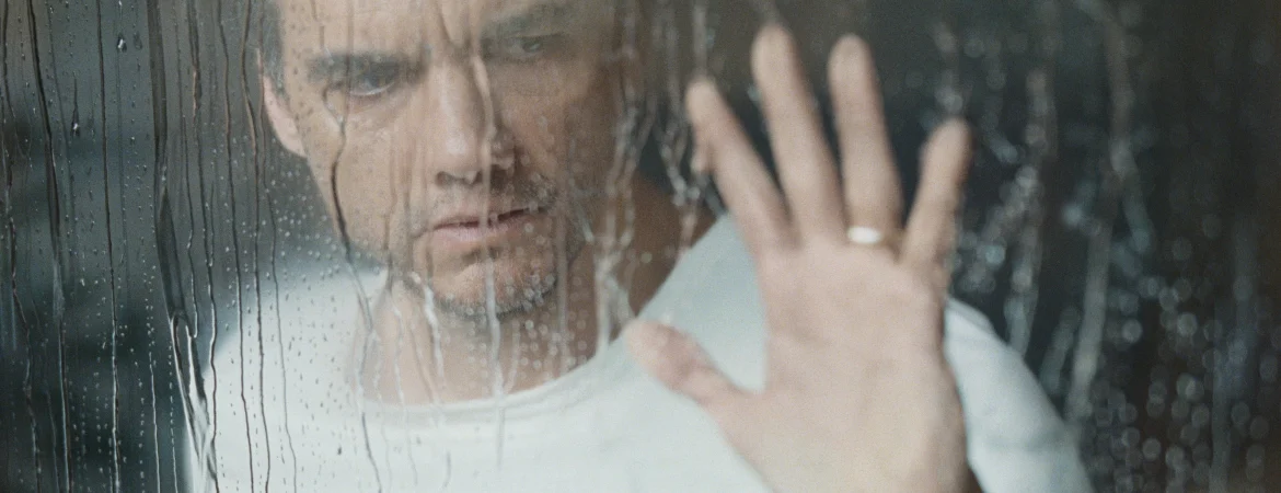 Un homme en tee shirt blanc (Wagner Moura) pose sa main sur une vitre ou coule de l'eau. Il semble inquiet et soucieux