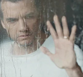 Un homme en tee shirt blanc (Wagner Moura) pose sa main sur une vitre ou coule de l'eau. Il semble inquiet et soucieux