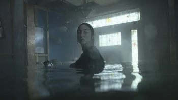 Une femme d'origine asiatique dans une maison visiblement inondée.