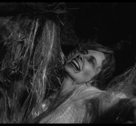 Personnage féminin coincée dans ce qui ressemble à de longs fils épais pour faire un cocon ; plan issu du film la bête de la caverne hantée de Monte Hellman.
