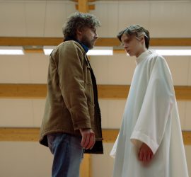 Un face à face entre un homme et l'enfant saint du film , dans un gymnase ; plan issu du film The Holy boy de Paolo Strippoli.