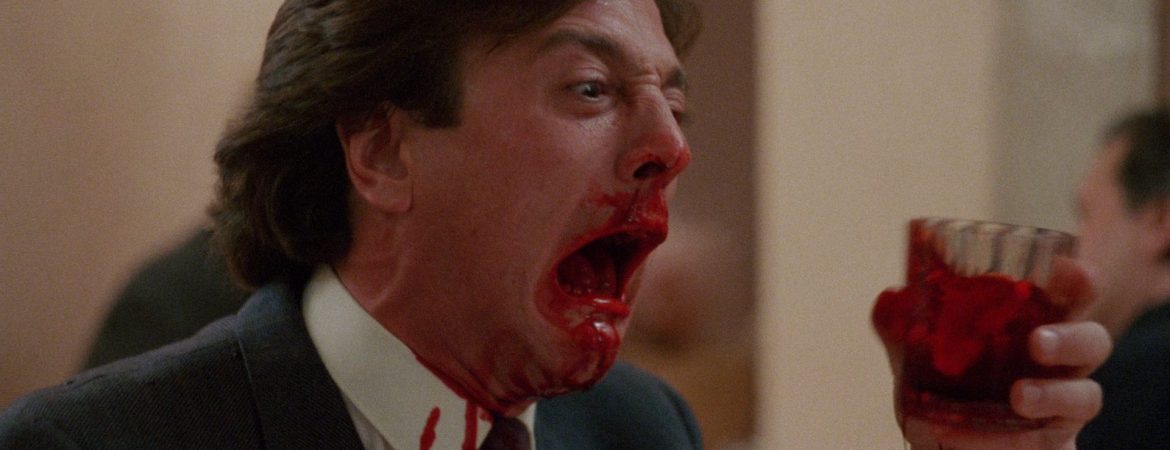 Slugs (1988) : homme ensanglanté tenant un verre rouge dans une scène gore.