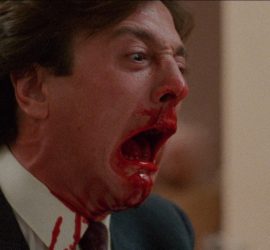 Slugs (1988) : homme ensanglanté tenant un verre rouge dans une scène gore.