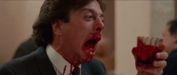 Slugs (1988) : homme ensanglanté tenant un verre rouge dans une scène gore.