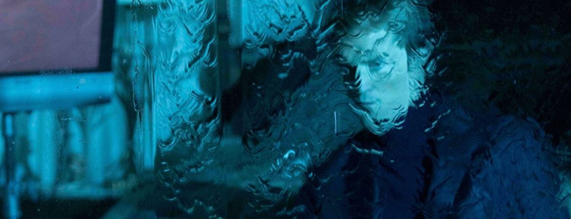 Robert Pattinson vu derrière une vitre troublée par une intense pluie ; plan issu du film Primetime.