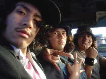 3 latinos alignés dans une voiture ; regardant la caméra ; cheveux longs bruns et bouclés avec casquettes et bonnets ; plan issu du film wassup rockers de Larry Clark.