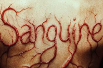 marion-le-corroller-sanguine-affiche-entretien-2026. Sur une surface de peau humaine filmée en très gros plan, le mot « Sanguine » apparaît en lettres cursives rouge sang, comme profondément gravé dans la chair ; les lettres, épaisses et en relief, se prolongent en fines ramifications semblables à des veines, formant un réseau de cicatrices rougeâtres sur la peau pâle ; affiche du film SANGUINE de Marion Le Corroller.