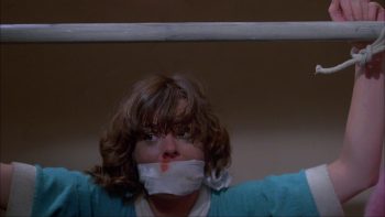 Jeune fille au nez ensanglanté ; attaché par des cordelettes à une tringle et bâillonné ; plan issu du film le silence qui tue de Denny Harris.