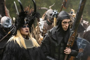 Personnages en costumes de guerriers fantastiques, dont une femme aux cornes recourbées et aux longs cheveux blonds et un combattant en armure noire, dans Le Roi du Game d'Éric Judor.