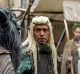 Éric Judor, vêtu d'un costume médiéval et portant une longue perruque blonde ainsi qu'un diadème, incarne un personnage elfique dans Le Roi du Game.